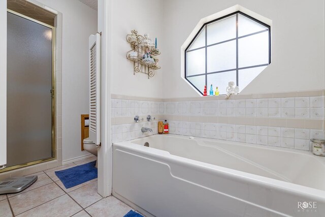 full bathroom featuring toilet, a shower stall, a bath, and tile patterned floors