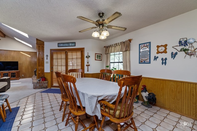 dining area with a wainscoted wall, a textured ceiling, and wooden walls