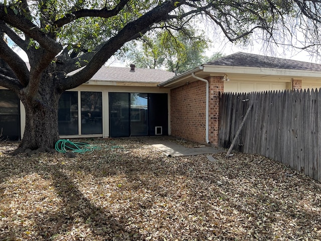 3222 Southland Blvd, San Angelo, TX 76904 - back of house featuring brick siding, roof with shingles, a sunroom, and an attached garage