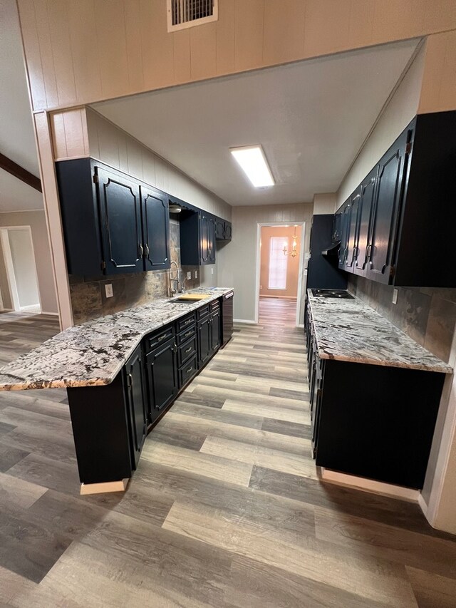 3222 Southland Blvd, San Angelo, TX 76904 - kitchen featuring dark cabinetry, light wood-style flooring, tasteful backsplash, and a peninsula