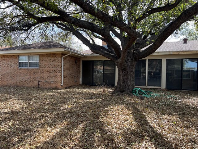 3222 Southland Blvd, San Angelo, TX 76904 - view of side of property with brick siding, a sunroom, and roof with shingles