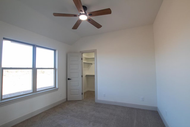 unfurnished bedroom featuring multiple windows, a walk in closet, ceiling fan, and a closet