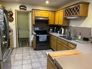 kitchen featuring electric range oven, sink, stainless steel refrigerator, and decorative backsplash