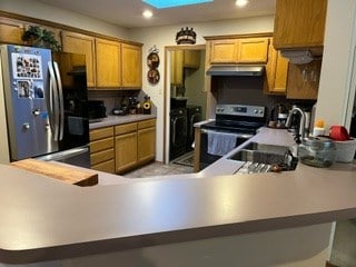 kitchen featuring stainless steel appliances, kitchen peninsula, sink, and washer and dryer