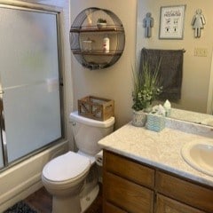 full bathroom featuring vanity, toilet, and combined bath / shower with glass door