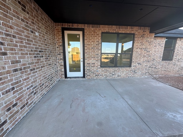 property entrance with a patio area and brick siding