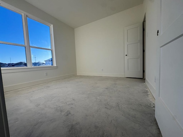 empty room with concrete flooring and baseboards