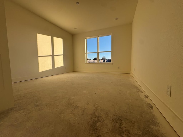 spare room featuring concrete flooring and vaulted ceiling