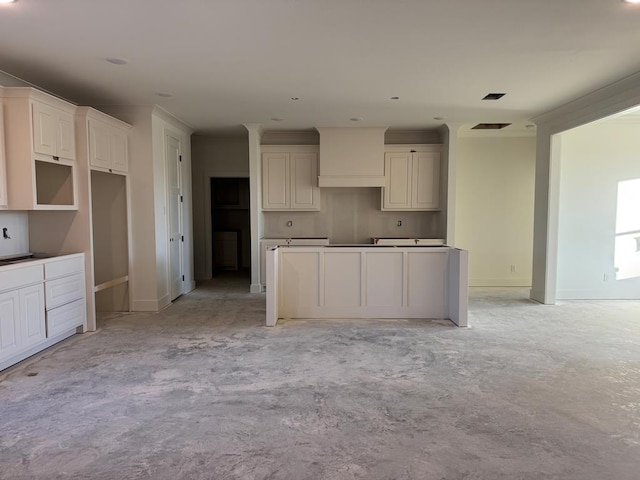 kitchen featuring concrete flooring, baseboards, visible vents, and white cabinets