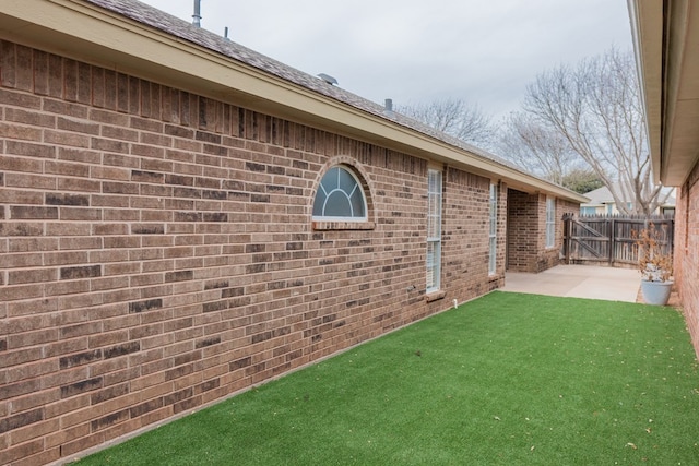 exterior space featuring a patio area, brick siding, fence, and a lawn