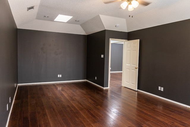 unfurnished room featuring dark wood-style floors, baseboards, visible vents, and vaulted ceiling