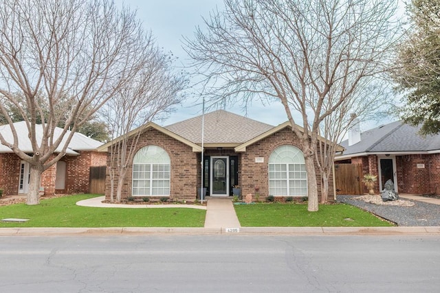 single story home with roof with shingles, a front lawn, and brick siding