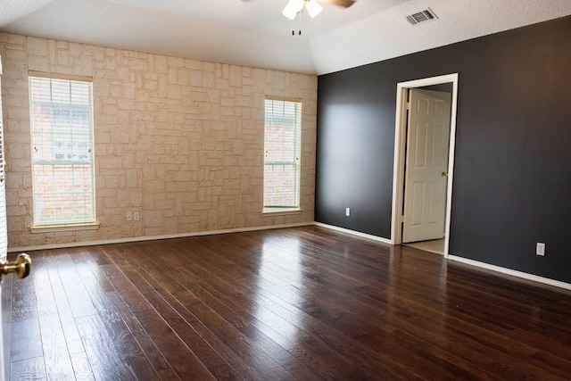 empty room featuring dark wood-style floors, lofted ceiling, visible vents, ceiling fan, and baseboards
