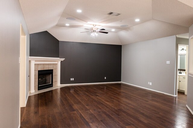 unfurnished living room with baseboards, visible vents, a tile fireplace, lofted ceiling, and dark wood-type flooring