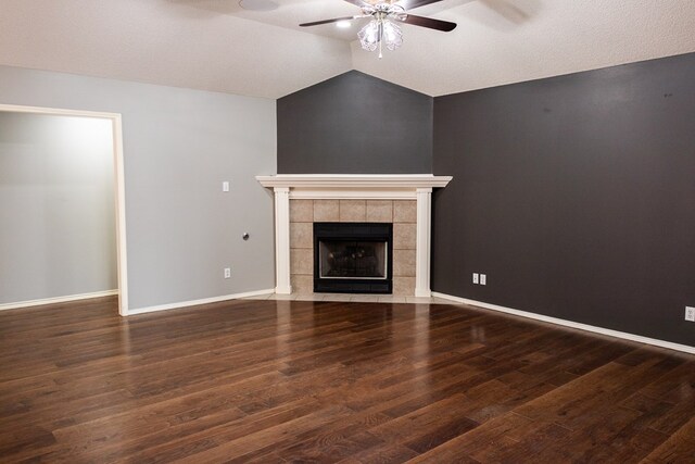 unfurnished living room featuring lofted ceiling, ceiling fan, wood finished floors, baseboards, and a tiled fireplace