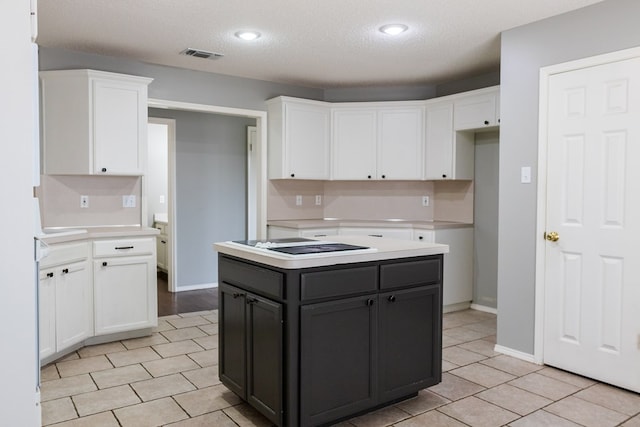 kitchen featuring light tile patterned floors, light countertops, white cabinets, dark cabinets, and black electric cooktop