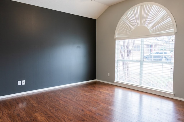 spare room with lofted ceiling, baseboards, and wood finished floors