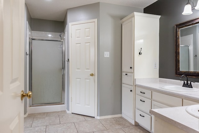 full bathroom featuring tile patterned flooring, baseboards, vanity, and a shower stall