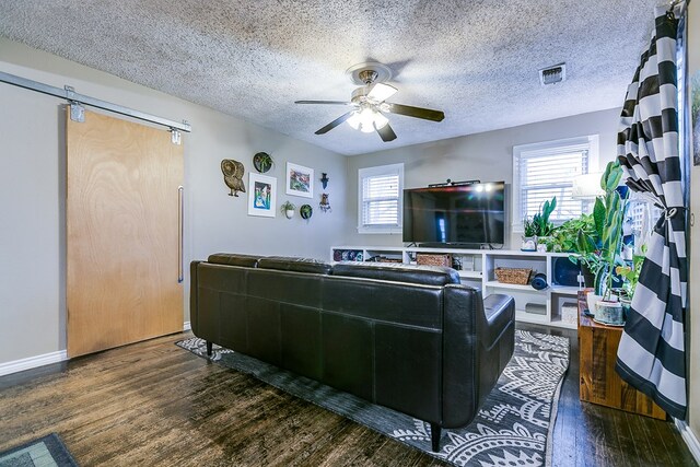 living room featuring ceiling fan, plenty of natural light, dark hardwood / wood-style flooring, and a textured ceiling