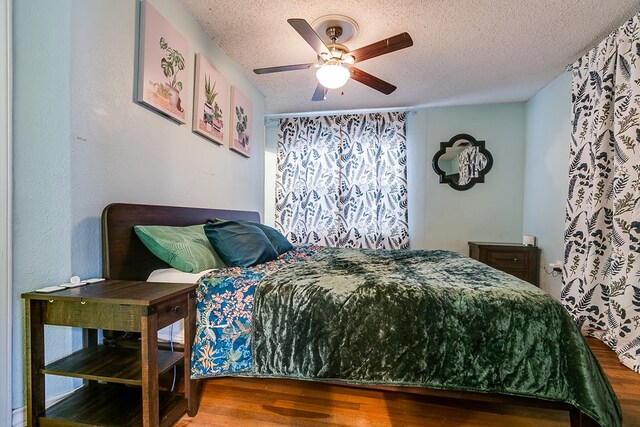 bedroom with hardwood / wood-style flooring, ceiling fan, and a textured ceiling