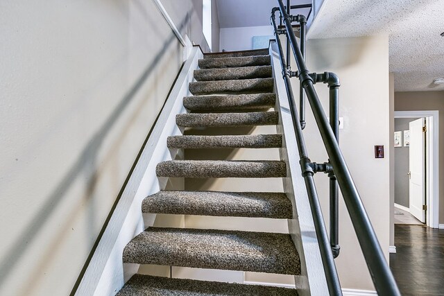 staircase with a textured ceiling