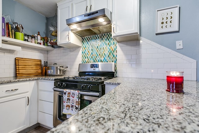 kitchen with ventilation hood, gas stove, light stone countertops, and white cabinets