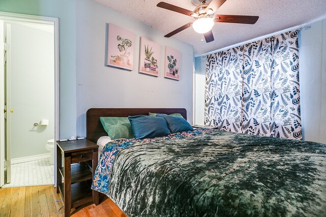 bedroom with ceiling fan, ensuite bathroom, a textured ceiling, and light hardwood / wood-style flooring