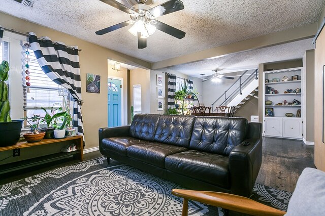 living room featuring dark hardwood / wood-style flooring, ceiling fan, and a textured ceiling