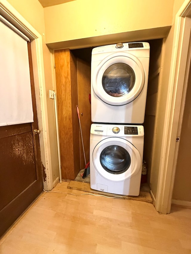 laundry area featuring stacked washing maching and dryer and light hardwood / wood-style floors