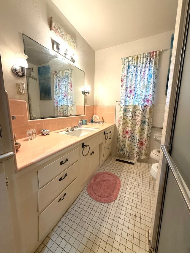 bathroom featuring toilet, a shower with curtain, tile walls, vanity, and tile patterned flooring