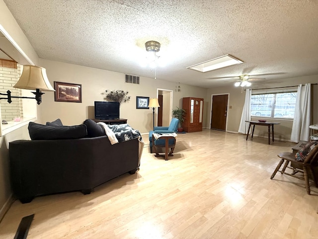 living room with ceiling fan, light hardwood / wood-style floors, and a textured ceiling