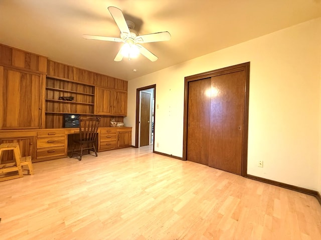 office area featuring built in desk, ceiling fan, and light wood-type flooring