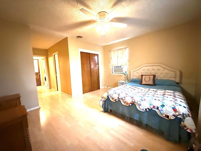 bedroom with wood-type flooring, a textured ceiling, a closet, cooling unit, and ceiling fan