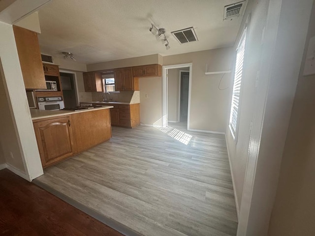 kitchen with white oven, sink, and light hardwood / wood-style floors