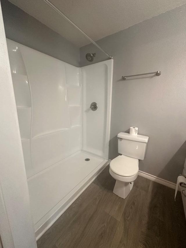 bathroom featuring a shower, hardwood / wood-style floors, and toilet