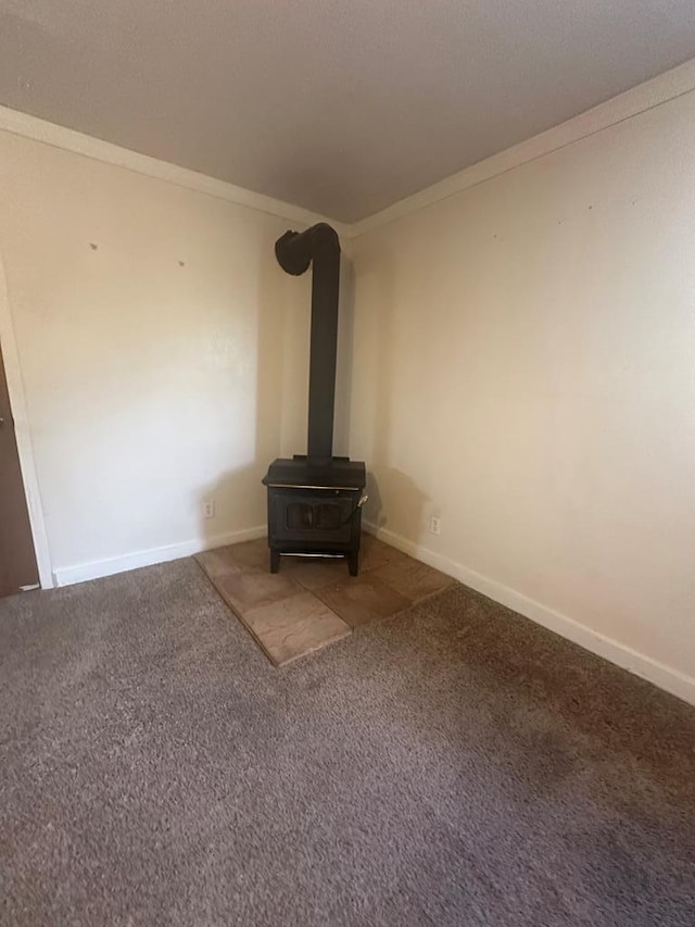 unfurnished living room featuring carpet flooring, ornamental molding, and a wood stove