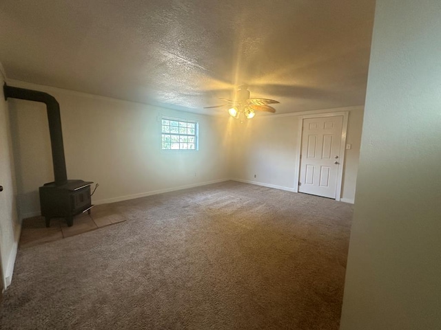 unfurnished living room with ceiling fan, a textured ceiling, carpet, and a wood stove