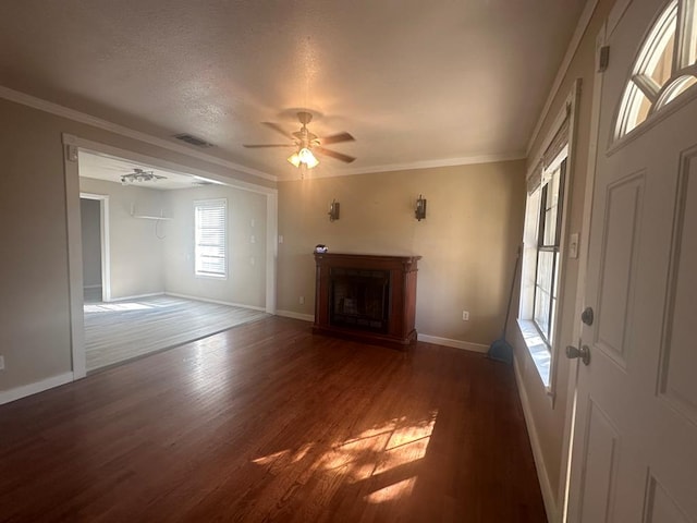 unfurnished living room with crown molding, ceiling fan, dark hardwood / wood-style flooring, and a textured ceiling