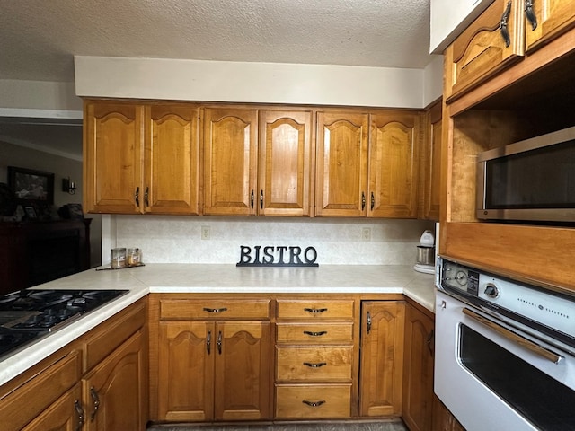 kitchen featuring tasteful backsplash, black gas stovetop, oven, and a textured ceiling