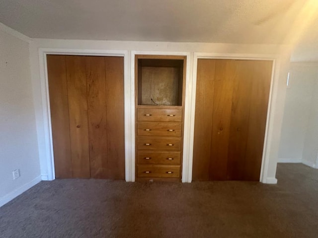 unfurnished bedroom featuring two closets and dark carpet