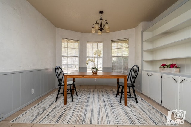 tiled dining room featuring a notable chandelier and built in features