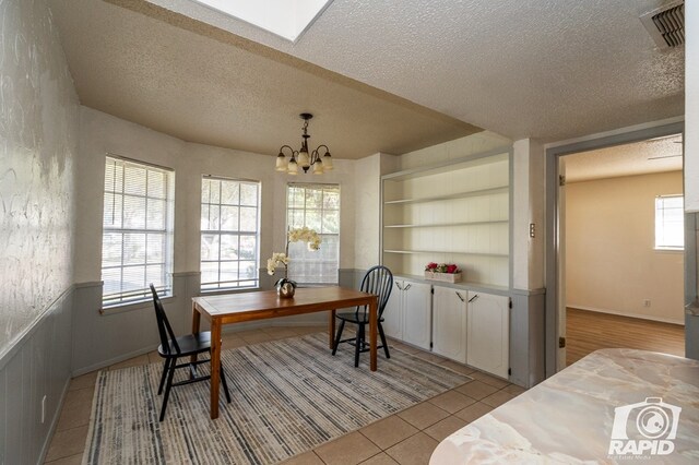 dining area with built in shelves, light tile patterned flooring, an inviting chandelier, and a wealth of natural light