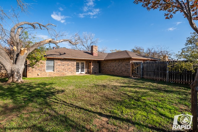 rear view of house with french doors and a yard