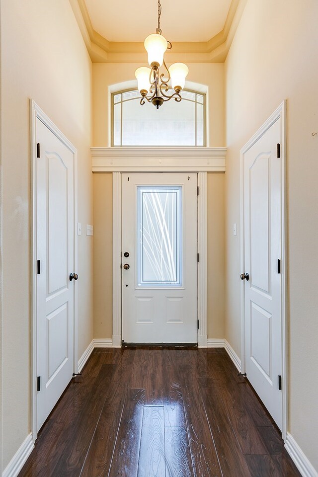 foyer entrance with dark wood-type flooring and an inviting chandelier