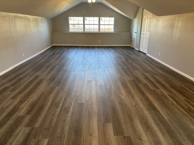 bonus room with vaulted ceiling and dark wood-type flooring