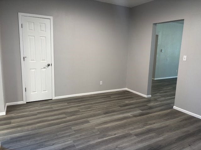 unfurnished room with dark hardwood / wood-style flooring