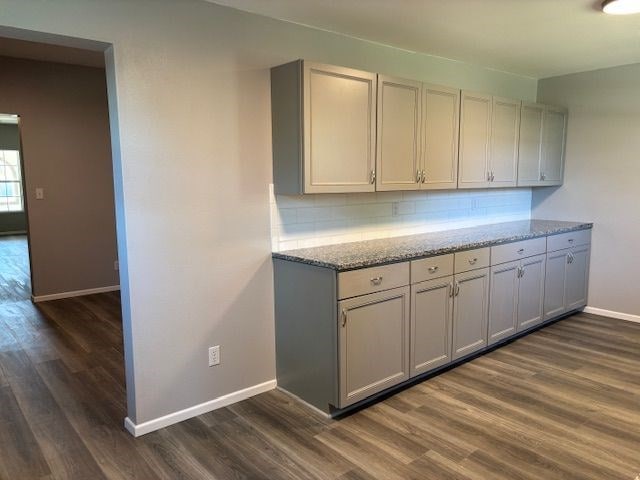 kitchen featuring tasteful backsplash, dark hardwood / wood-style flooring, and light stone countertops