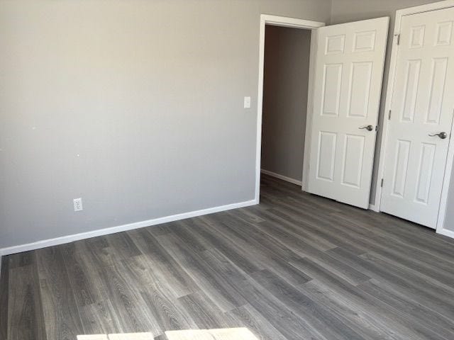 unfurnished bedroom with dark hardwood / wood-style flooring