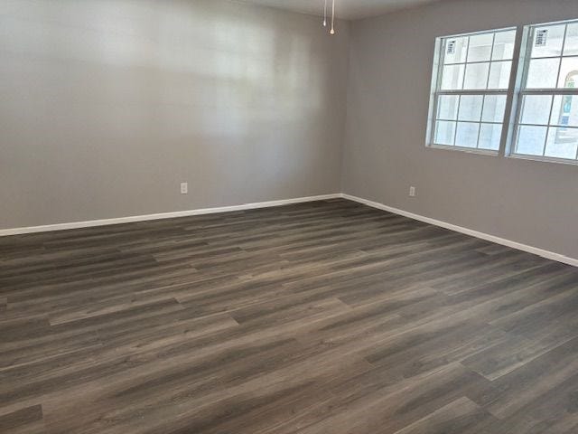 empty room with dark hardwood / wood-style floors and ceiling fan