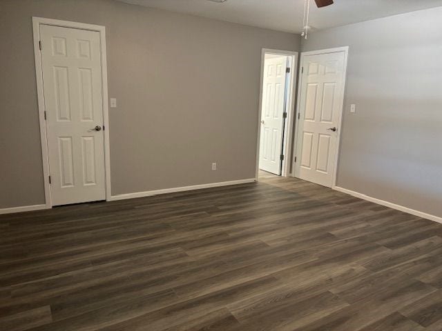 empty room with dark wood-type flooring and ceiling fan